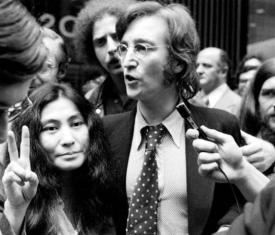 Yoko faz o sinal da paz e John responde aos repórteres depois de uma audiência do Departamento de Imigração e Naturalização, em maio de 1972/ Foto: Corbis